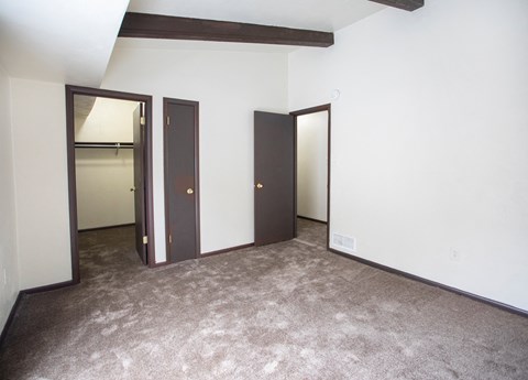 A room with carpeted floor and three doors.
