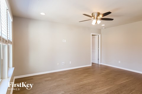 A room with a ceiling fan and wooden flooring.