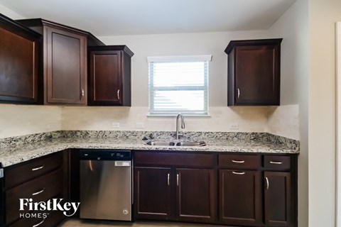 A kitchen with brown cabinets and a FirstKey Homes logo.