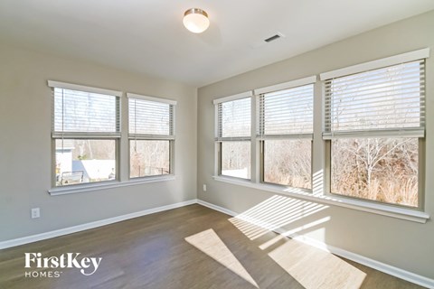 A room with a wooden floor and three windows with blinds.
