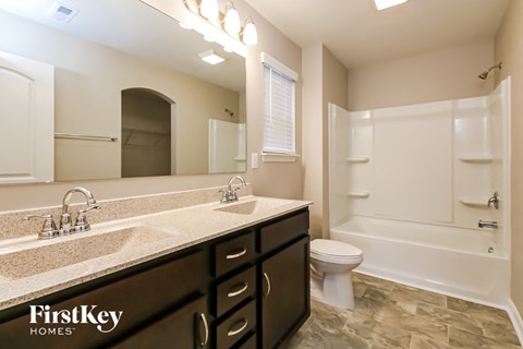 A bathroom with a double sink vanity and a bathtub.