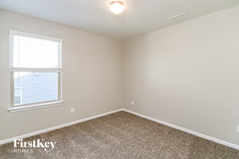 A room with a window and a carpeted floor.