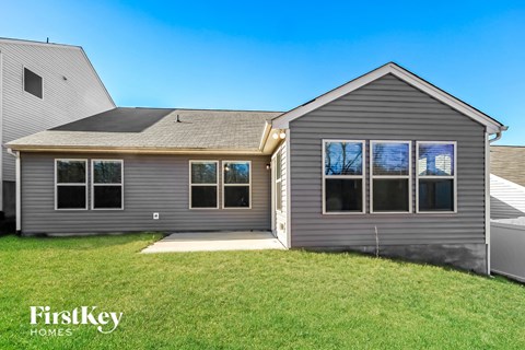 A grey house with a black roof and a white fence.