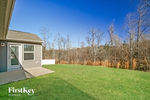 A house with a large lawn and trees in the background.