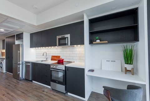 A modern kitchen with black cabinets and a white countertop.
