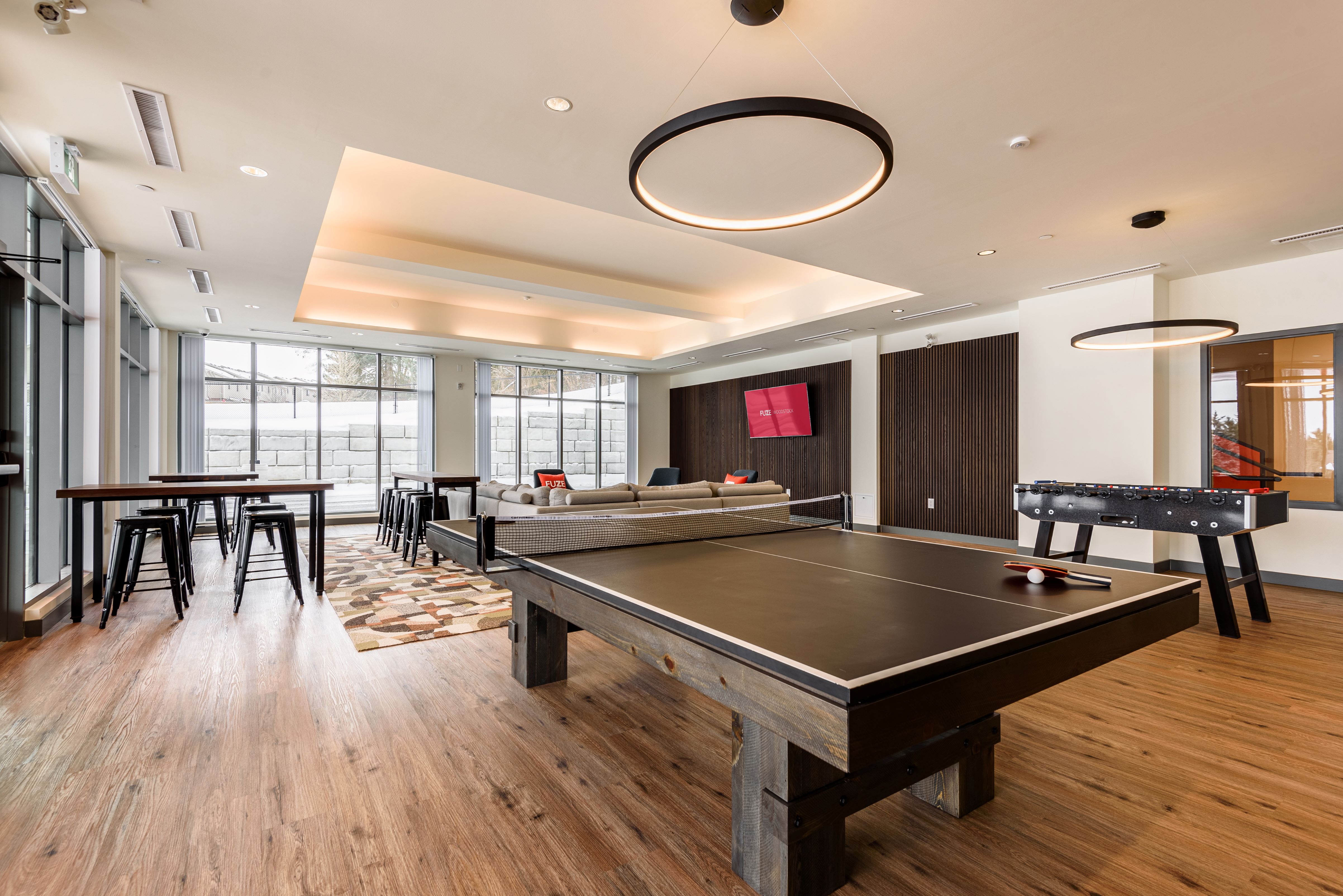 A ping pong table is in the middle of a room with a pool table and a bar.