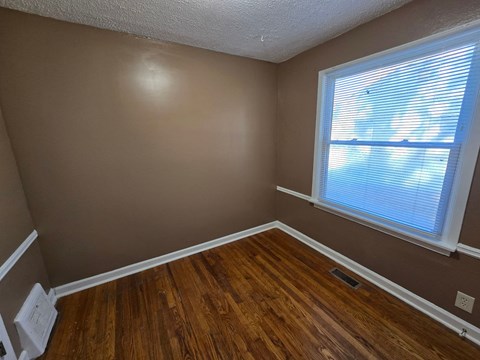 a bedroom with wood floors and a large window