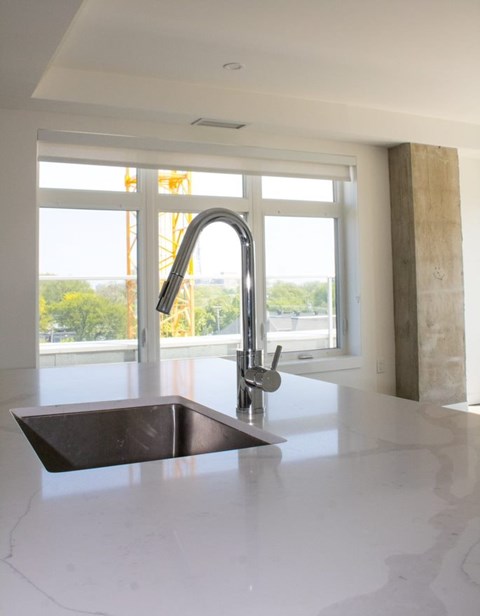 A kitchen sink with a faucet and a window in the background.