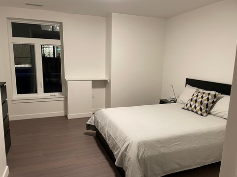 A bedroom with a bed, nightstand, and window.