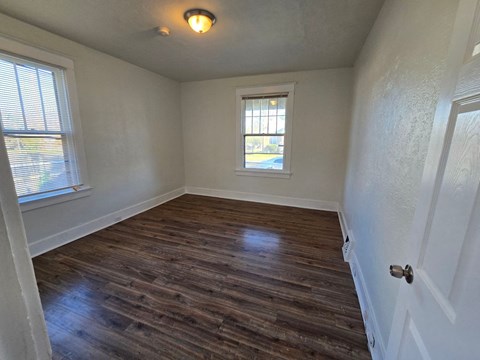 an empty living room with wooden floors and a window
