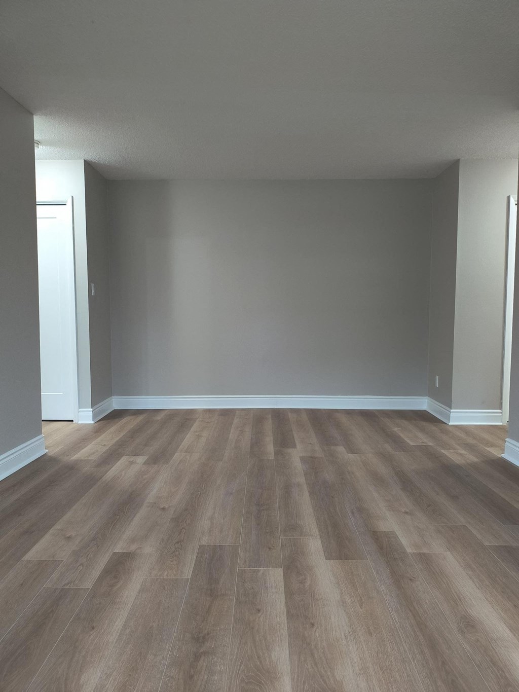 A room with wooden flooring and white walls.