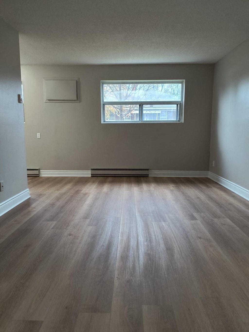 A room with a window and wooden flooring.