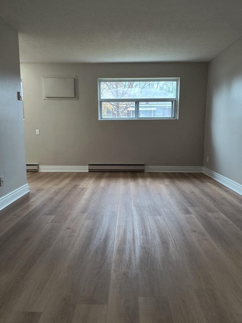 A room with a window and wooden flooring.