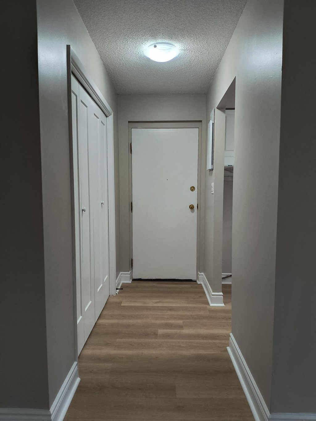 A long hallway with a white door at the end.