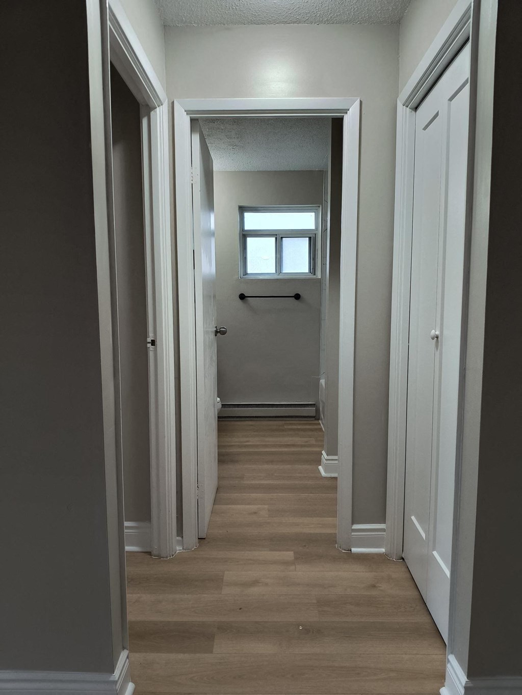A long, narrow hallway with a door on the left and a window on the right.