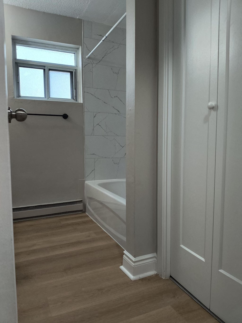 A white bathroom with a tub and a window.