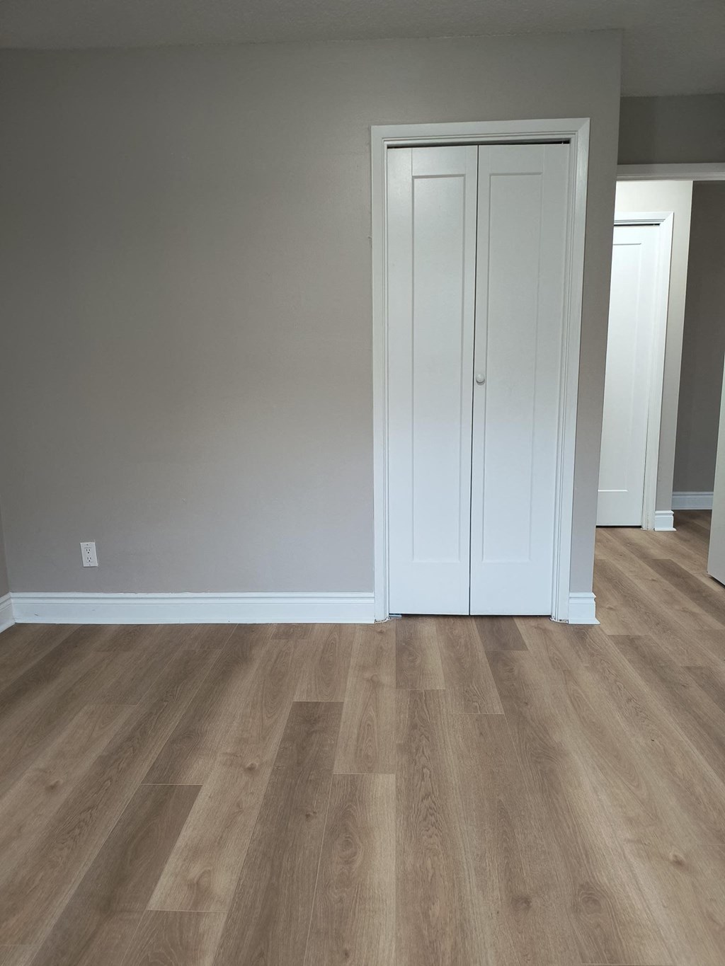 A white door is in a room with wood flooring.