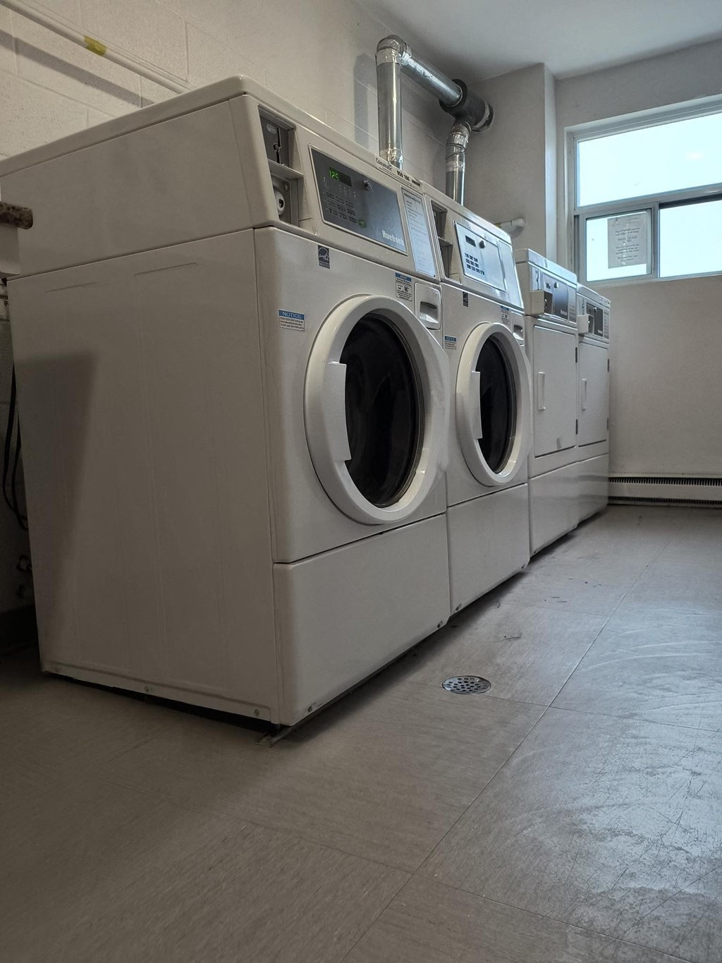 A row of industrial washing machines in a laundry room.