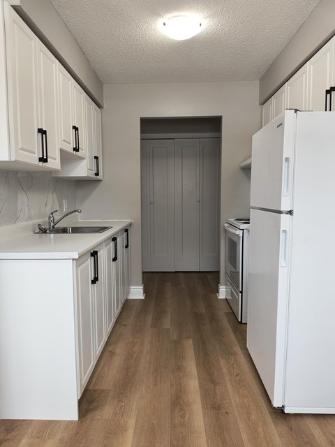 A kitchen with white cabinets and a white fridge.