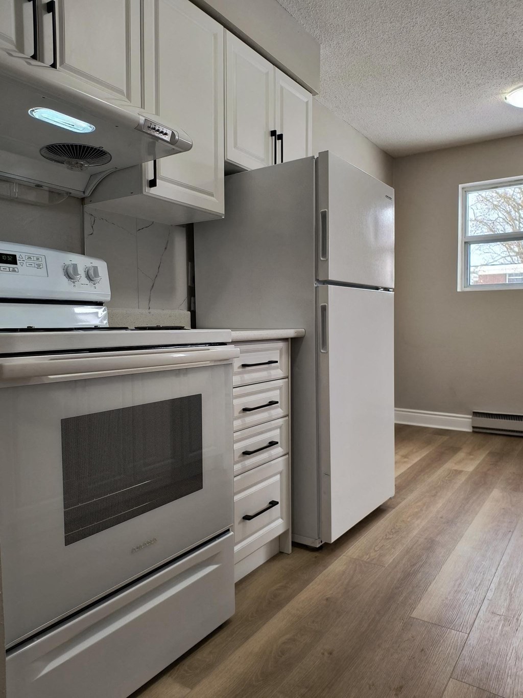 A kitchen with a white oven and refrigerator.