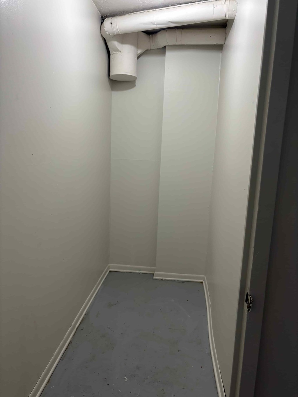 A white pipe runs along the wall of a narrow room.