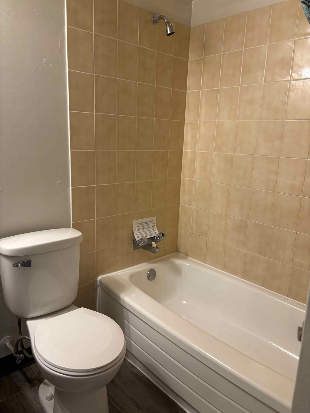 A white toilet sits next to a bathtub in a bathroom.