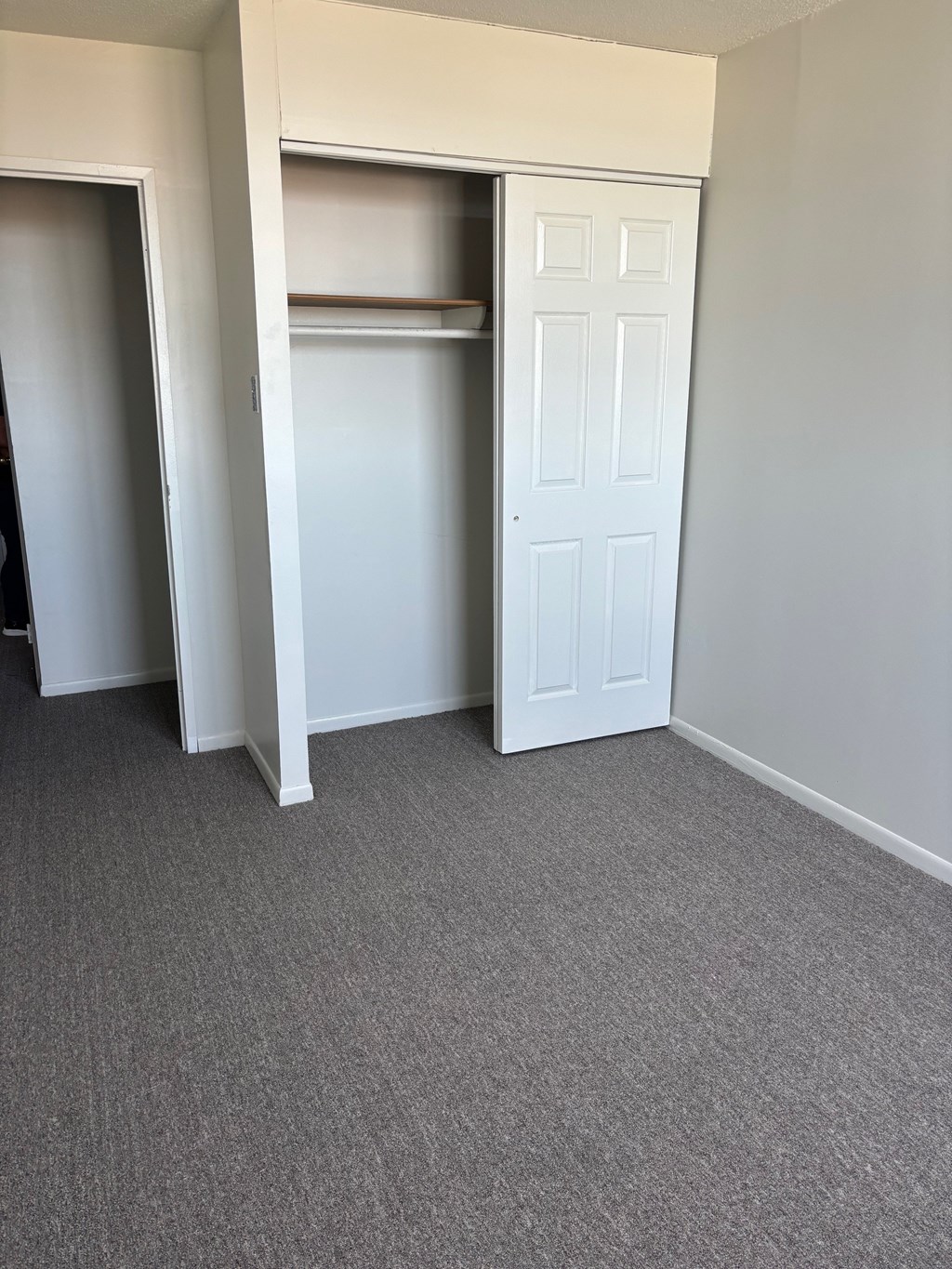 A white door is open in a room with grey carpet.