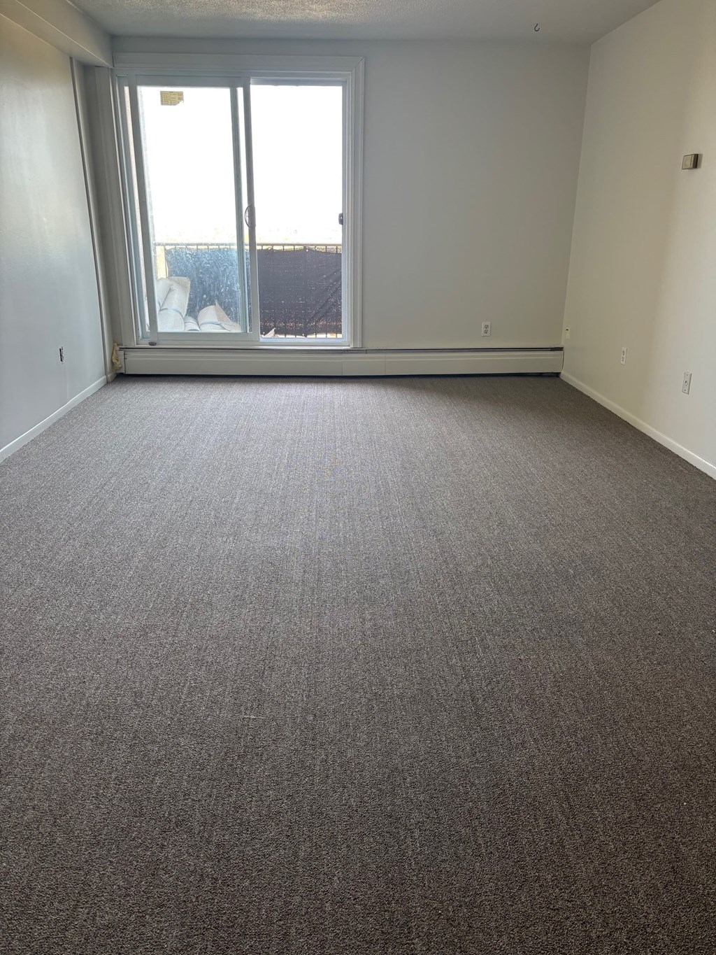 A room with a carpeted floor and a sliding glass door.