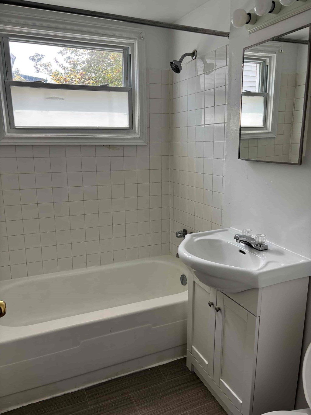 A white bathroom with a tub, sink, and mirror.