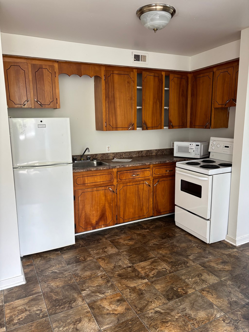 A kitchen with a white refrigerator, white stove, and wooden cabinets.