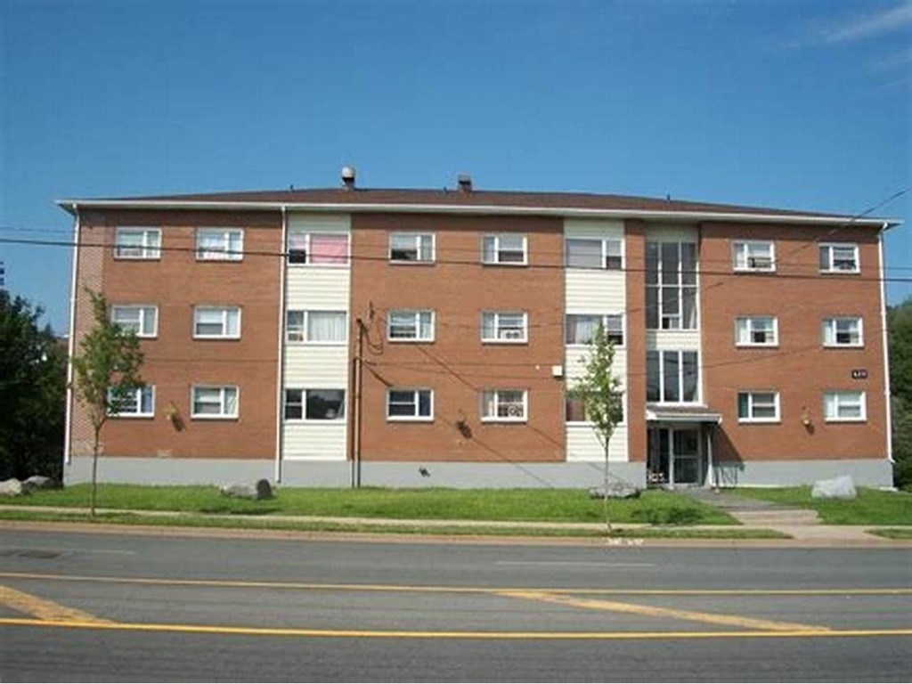 A large brick apartment building with a parking lot in front.