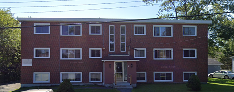 A red brick building with a white door and windows.