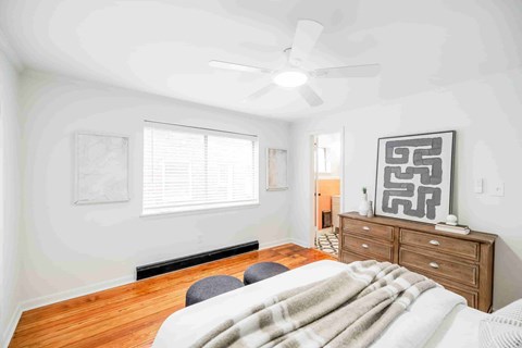 A bedroom with a bed, dresser, and ceiling fan.