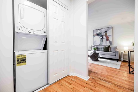 A white oven with a sticker on it is in a room with a grey couch and a painting on the wall.