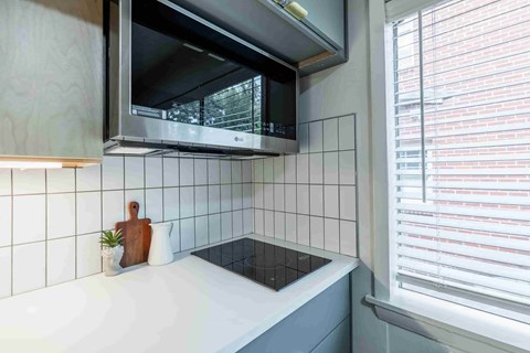 A modern kitchen with a stainless steel microwave above a white countertop.