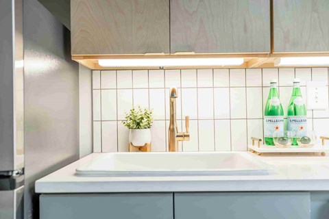 A kitchen with a white sink and a wooden cabinet.