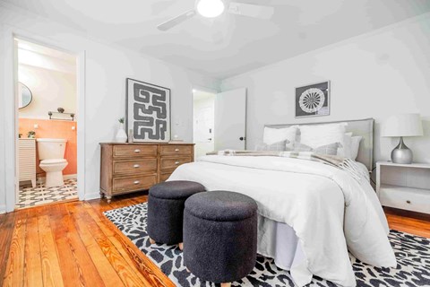 A bedroom with a white bed and a wooden floor.