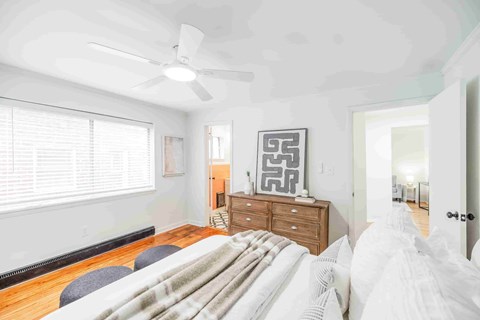A bedroom with a bed, dresser, and window.