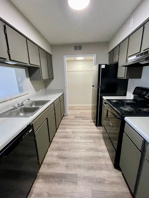 an empty kitchen with black appliances and white counters