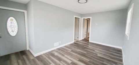 a renovated living room with wood flooring and a door to a hallway
