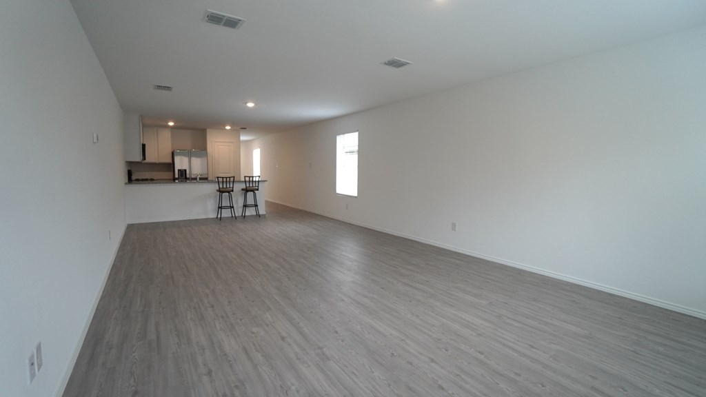 A large empty room with wooden flooring and white walls.