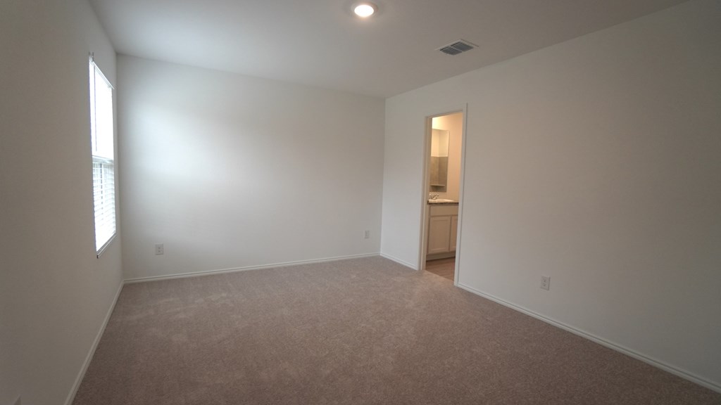 A room with a carpeted floor and a doorway leading to another room.