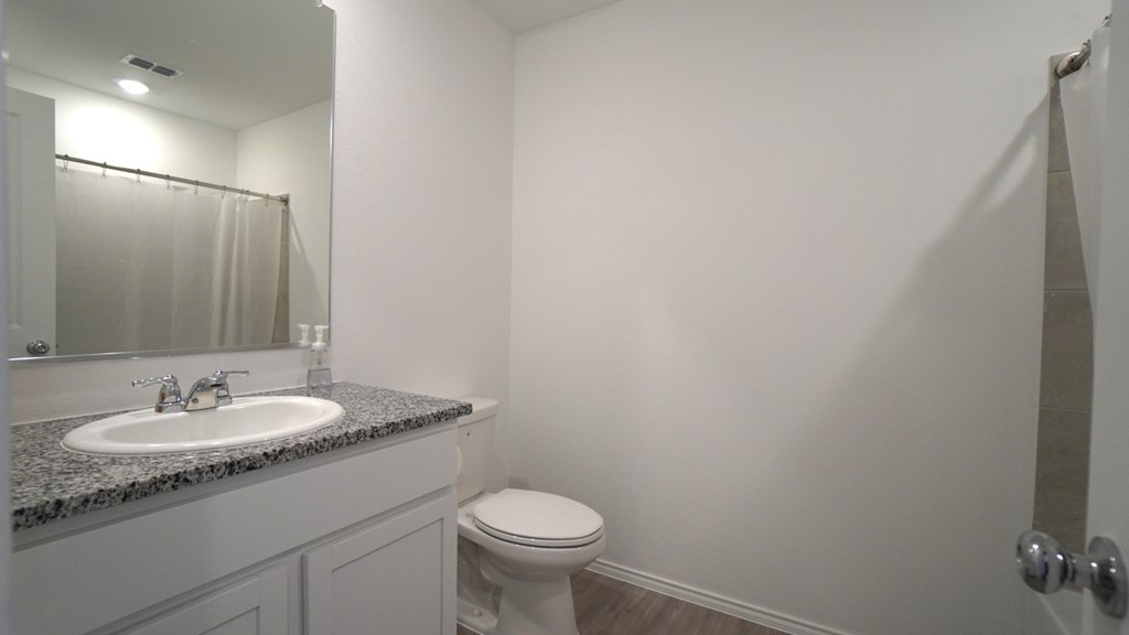 A bathroom with a sink, toilet and mirror.