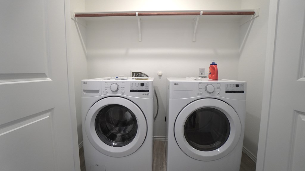 Two white front loading washing machines in a small laundry room.