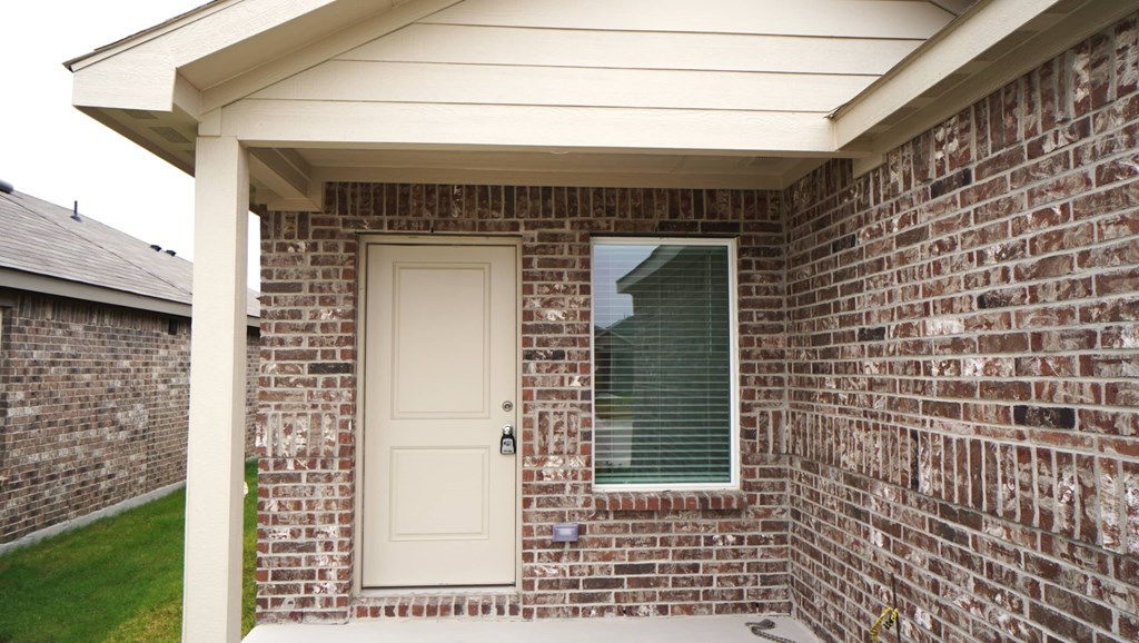 A white door is on the front of a brick house.