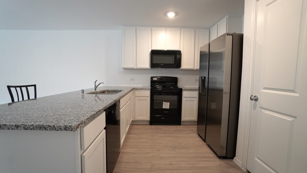 A kitchen with a black fridge and white cabinets.