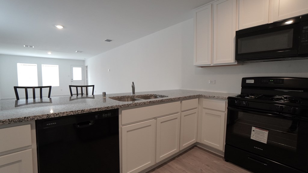 A kitchen with black appliances and white cabinets.