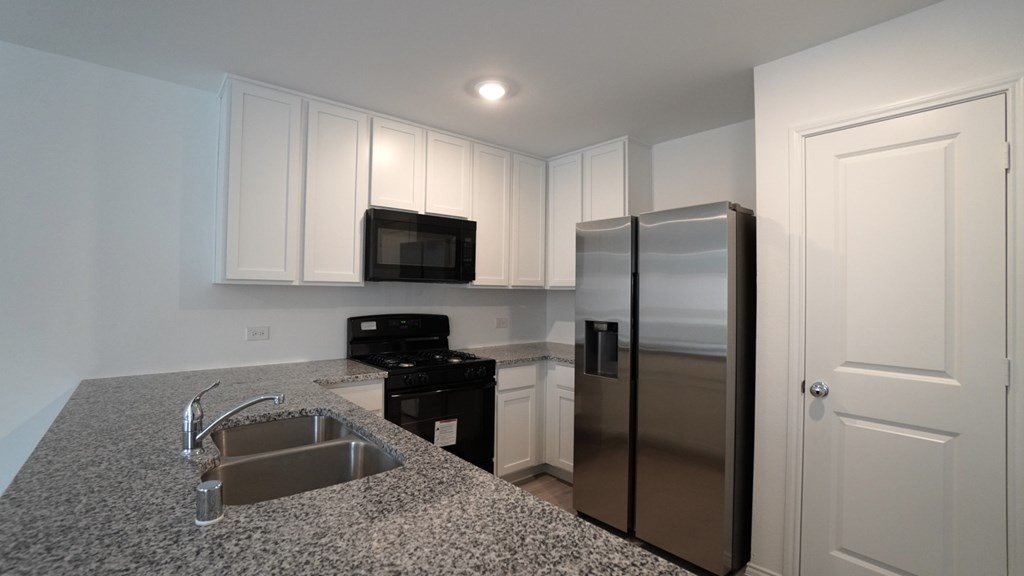A kitchen with a granite countertop and stainless steel appliances.