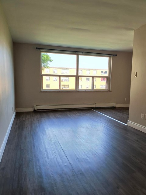A room with a large window and wooden flooring.