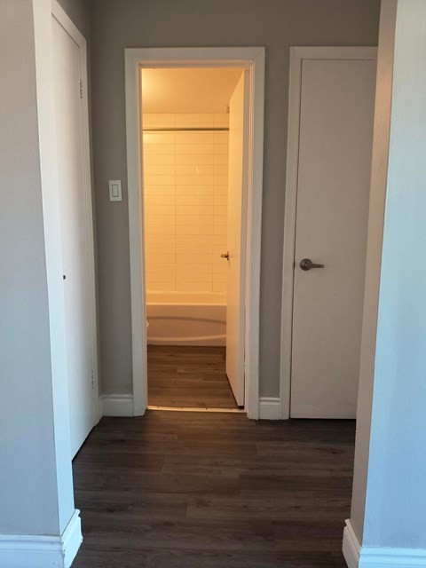 A hallway with a white door and a light switch on the wall.